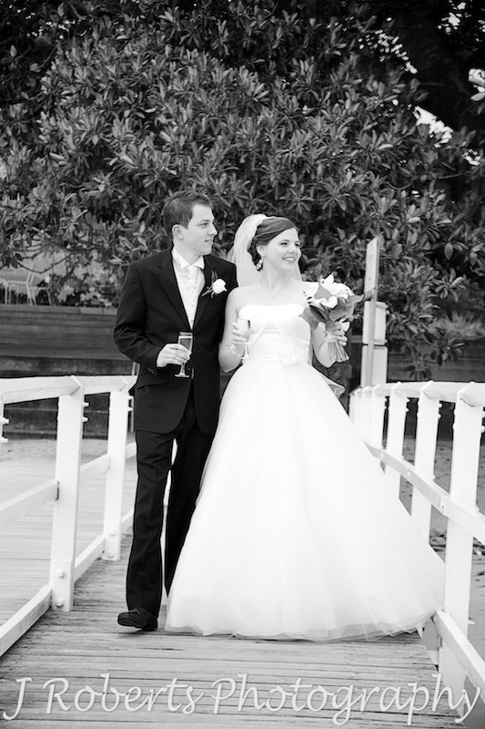 B&W of bride and groom walking along the boardwalk at Balmoral Baths - wedding photography sydney